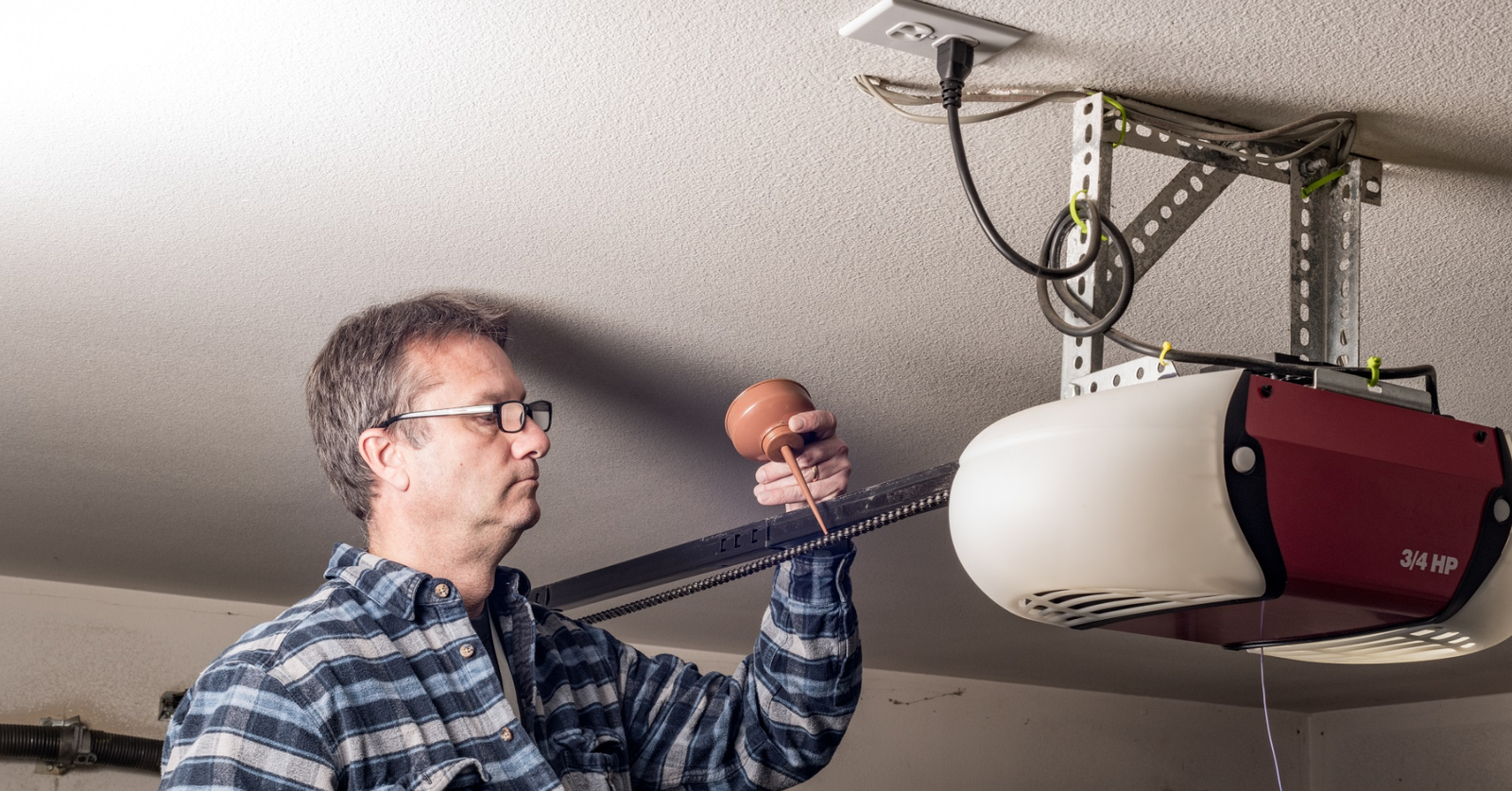 "Technician repairinga modern garage door opener in a residential garage at Sapphire Shores."