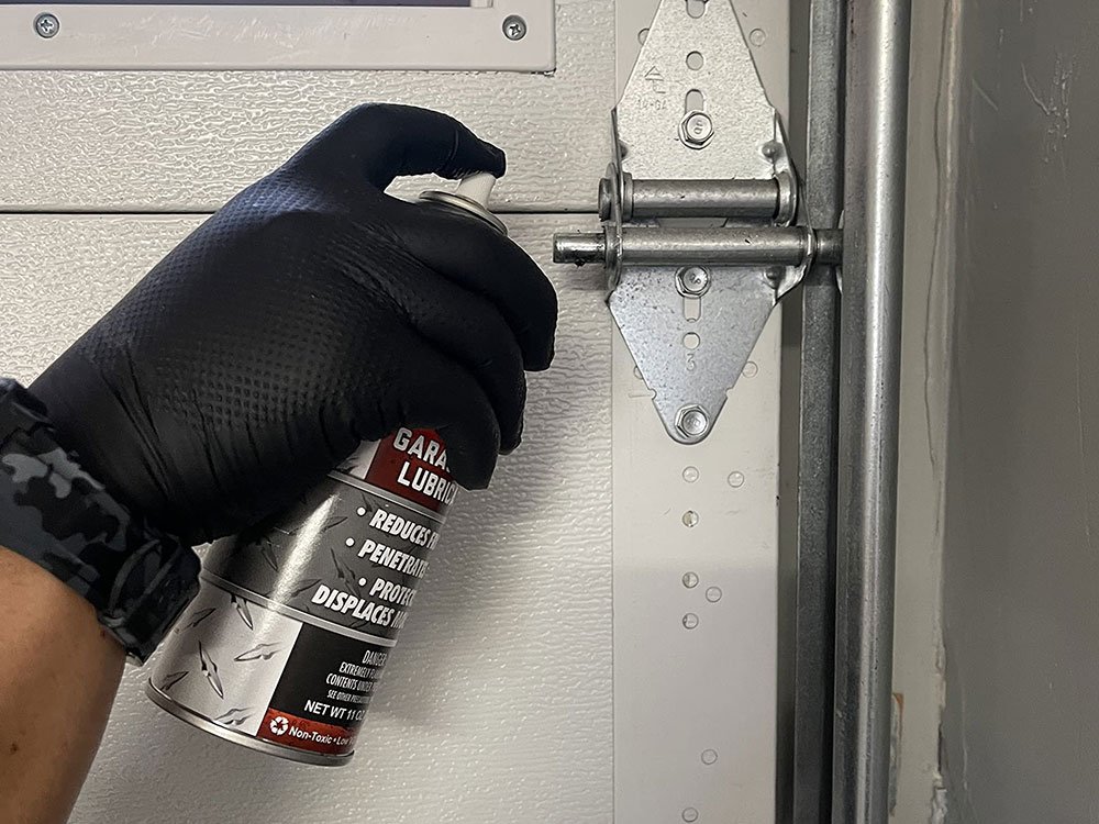 "Technician repairing a noisy garage door to ensure smooth operation and reduced noise levels"