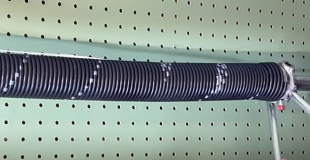 Technician repairing a garage door spring in a residential area of Sapphire Shores with the text 'GARAGE DOOR SPRING REPAIR' prominently displayed